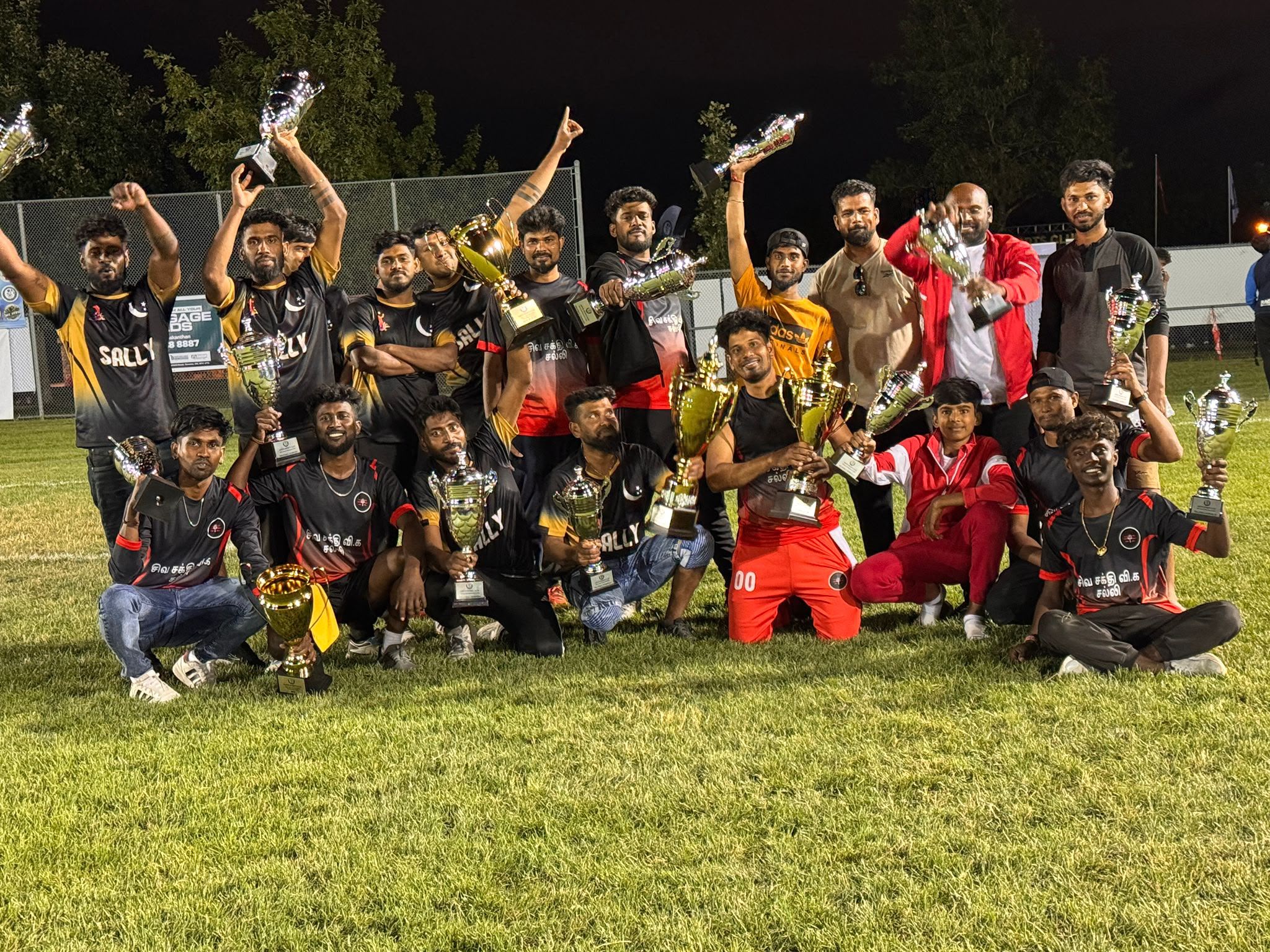 A winning team lifting trophies at night